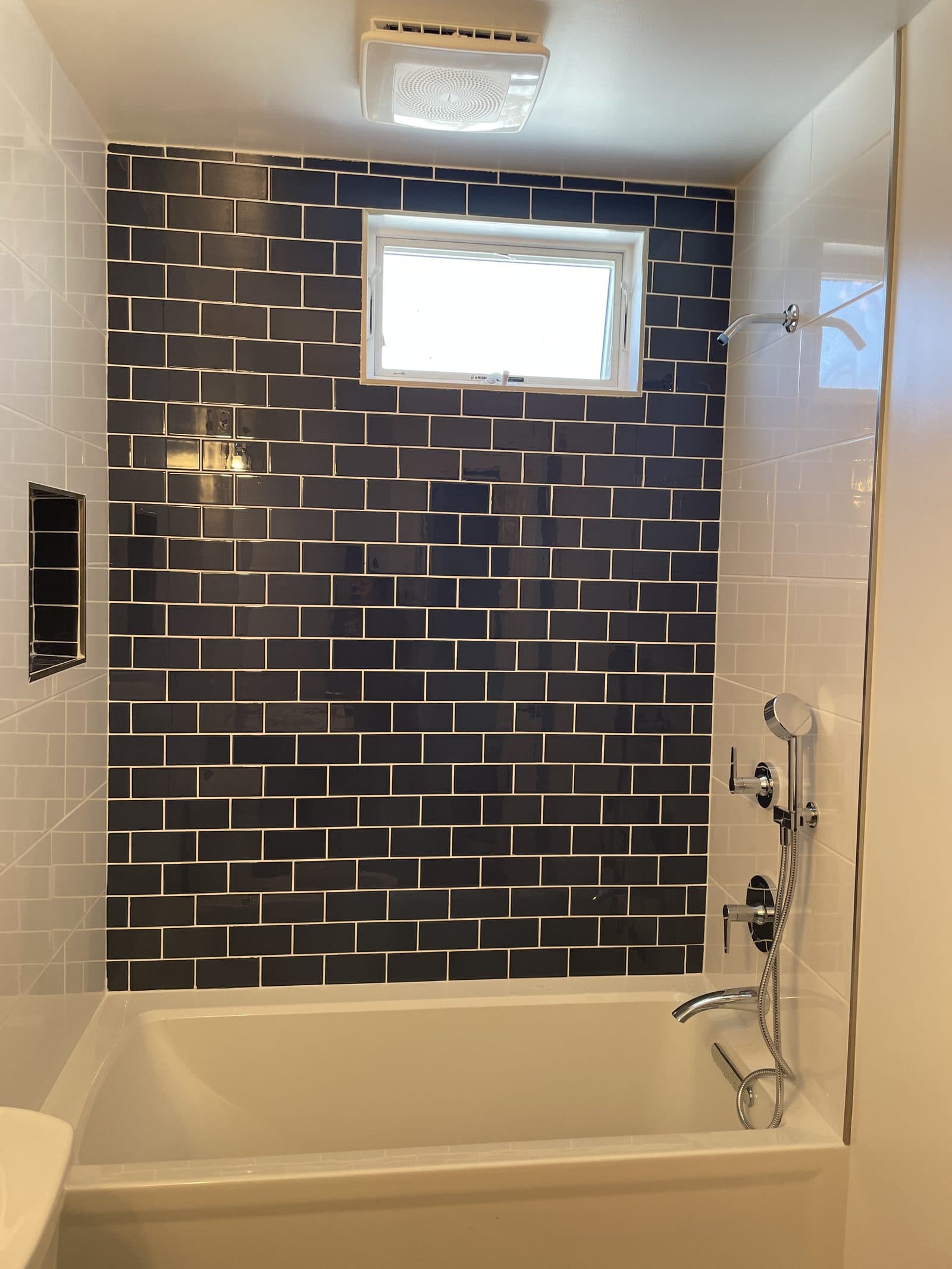 Dark-tiled shower with white tub