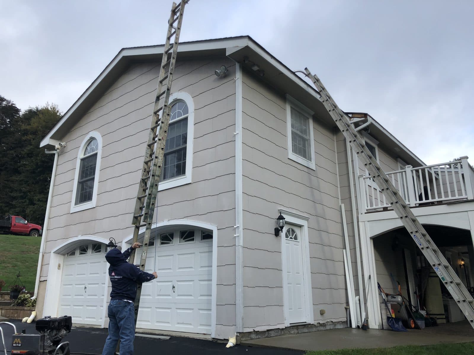 Worker on ladder painting house exterior