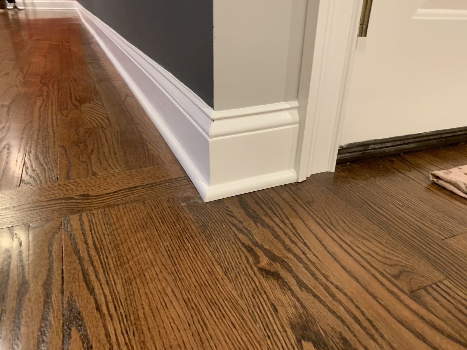 Refinished hardwood floor with white baseboard