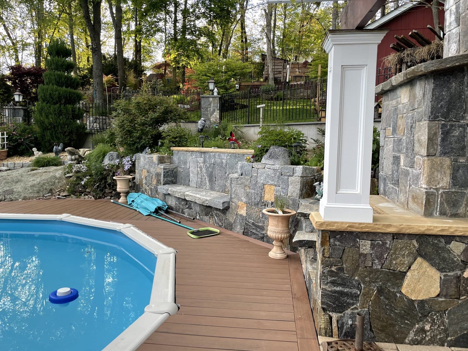 A backyard pool framed by a stone patio installed by C&C Fabian.