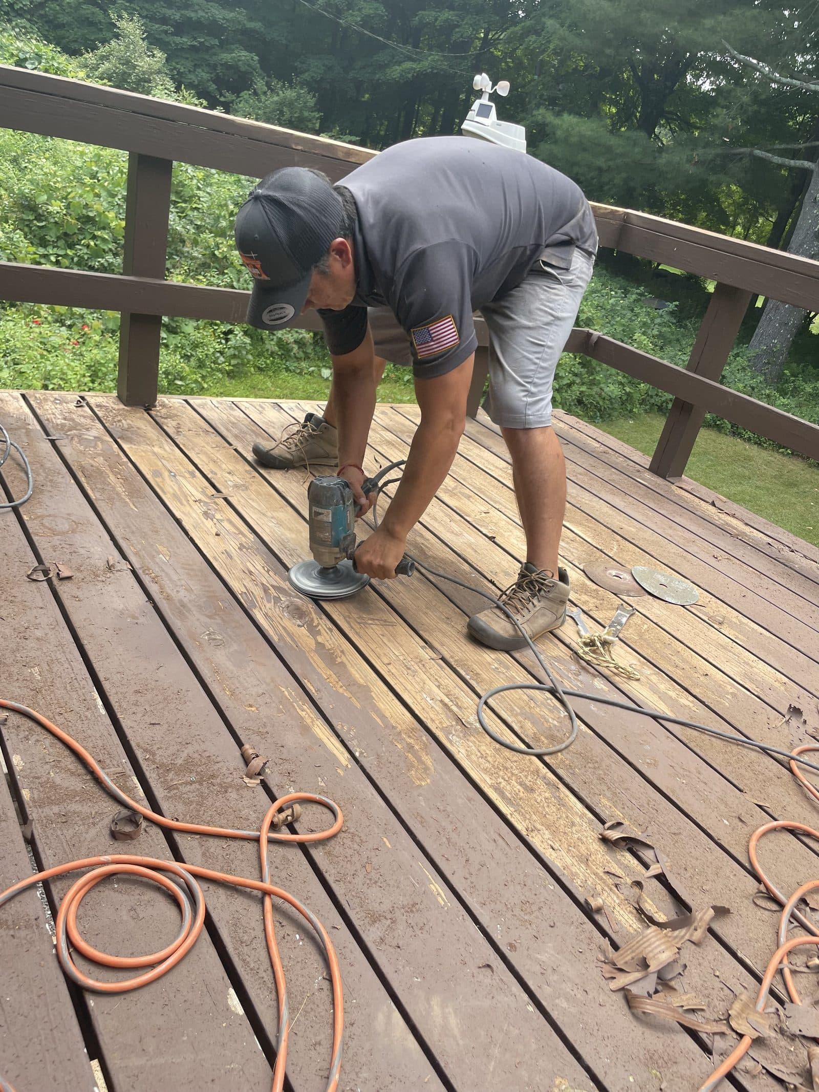 Worker power washing a wood deck to restore the finish.