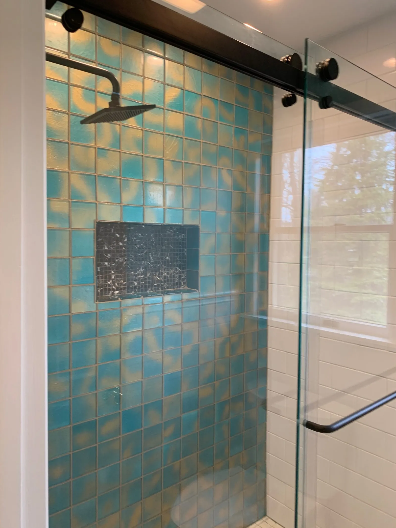 New walk-in shower with teal glass tile and a sliding glass door
