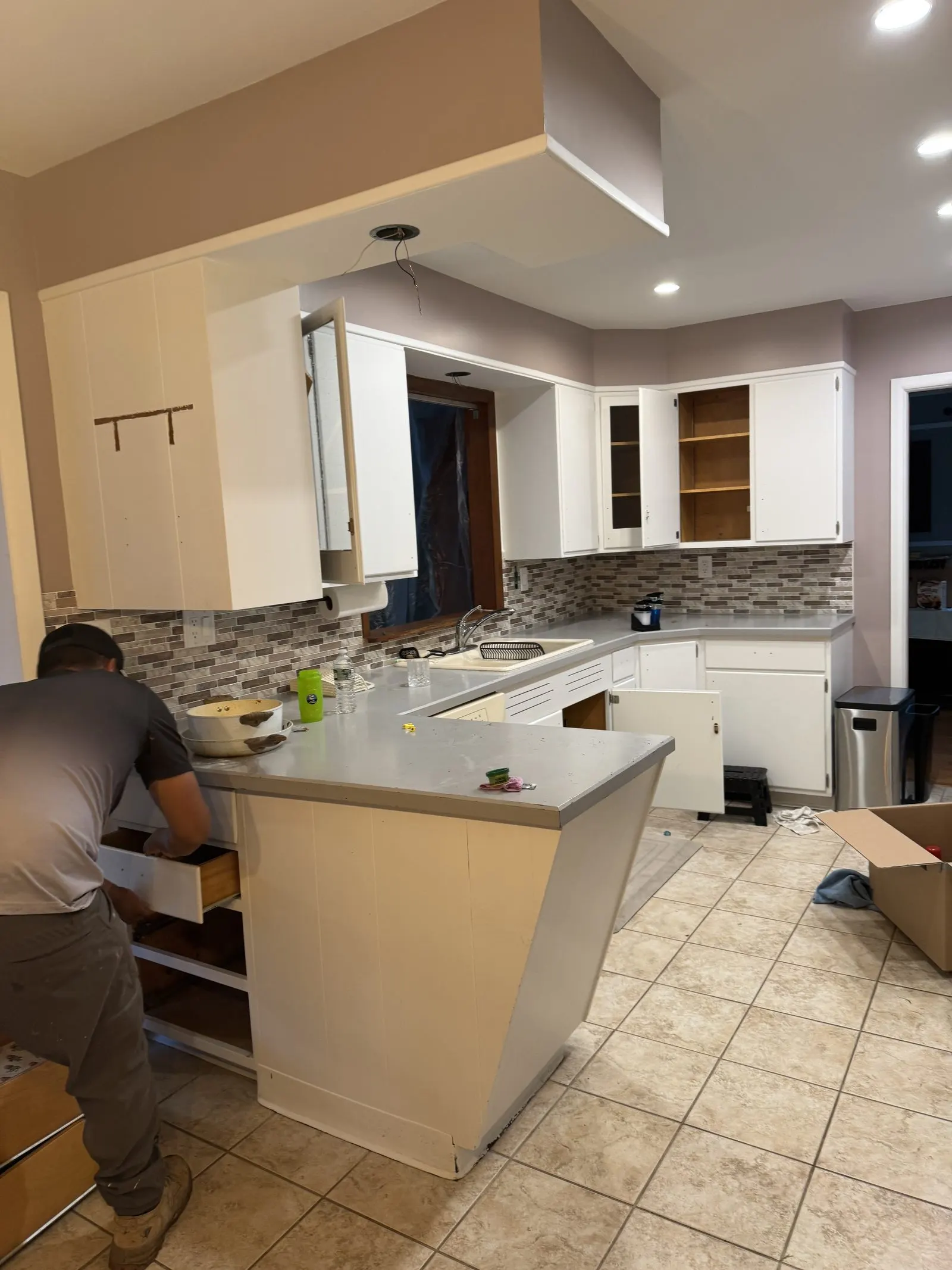 Original kitchen with white cabinets and dark backsplash before remodel