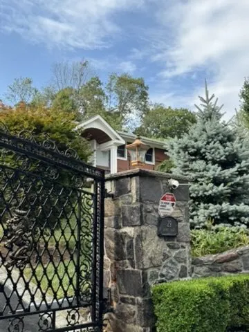 Ornamental iron driveway gate set between stone pillars
