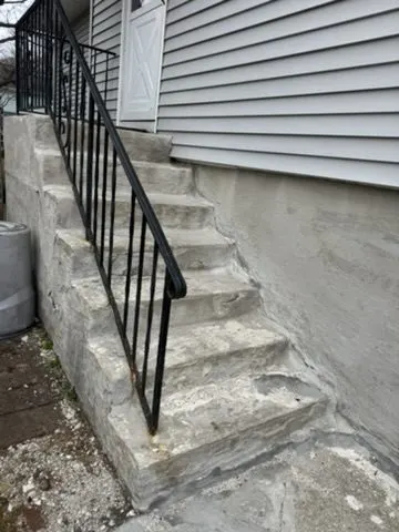 Black iron handrail installed along stone steps