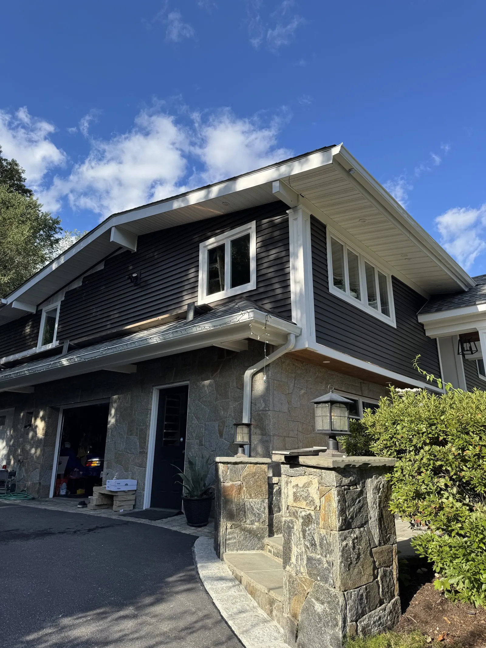 Dark gray sided home with stone pillars and white trim