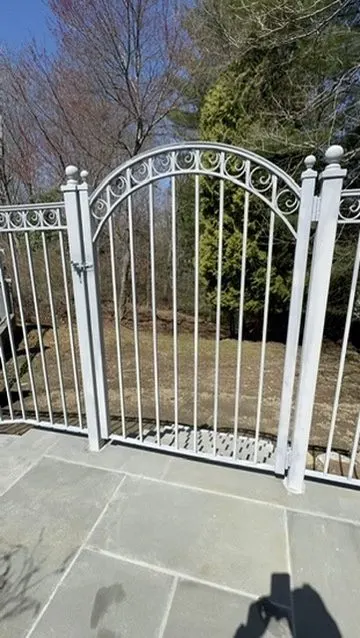 White ornamental arched garden gate on a stone patio