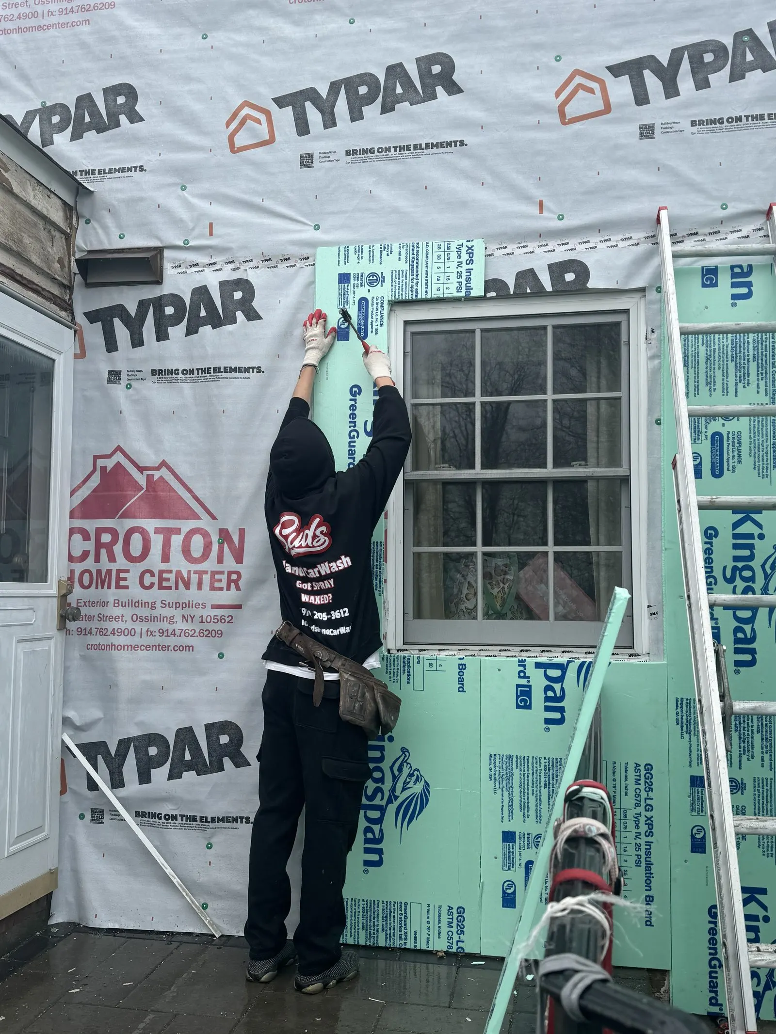 Crew member installing house wrap before new siding