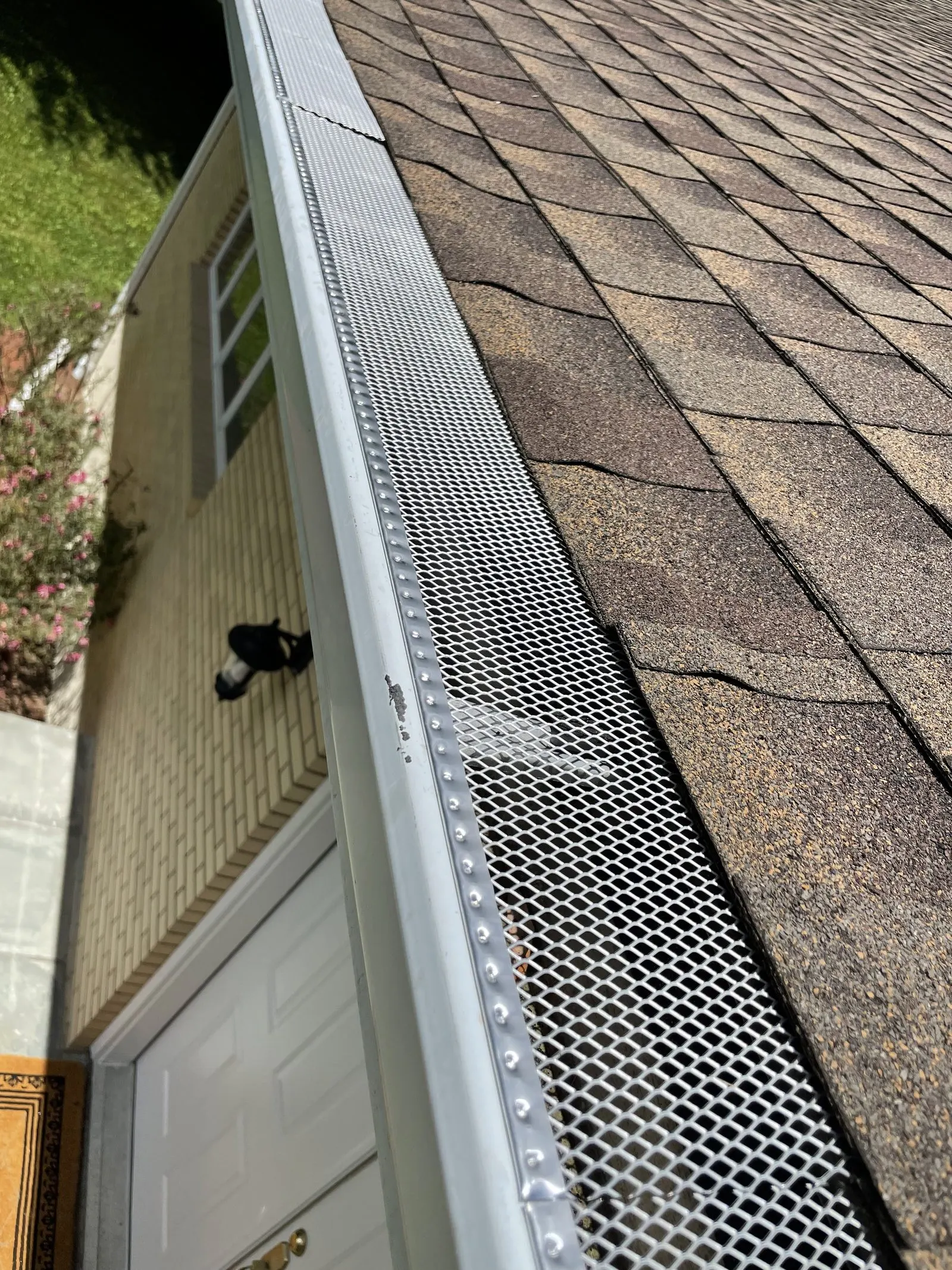 New aluminum gutter with mesh leaf guard installed along a roof edge