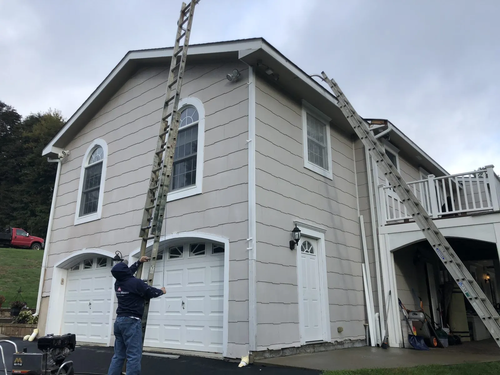 Worker on ladder painting house exterior