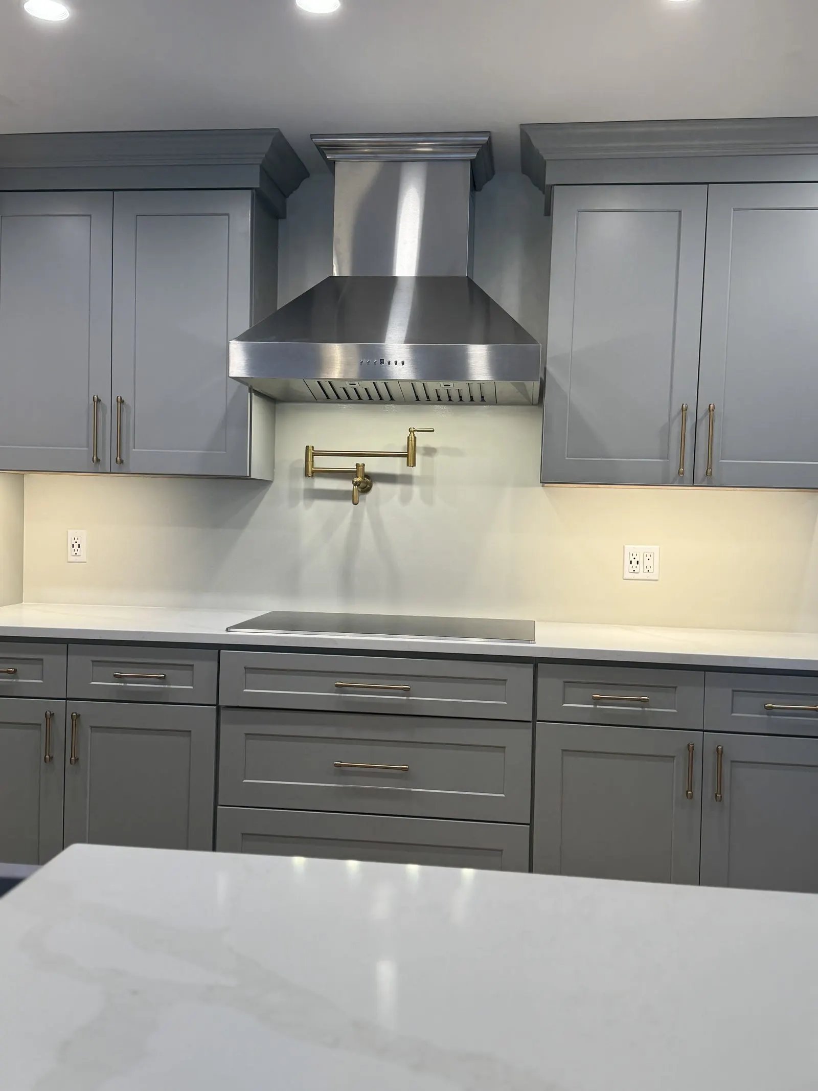 Stainless range hood and pot filler over a marble backsplash