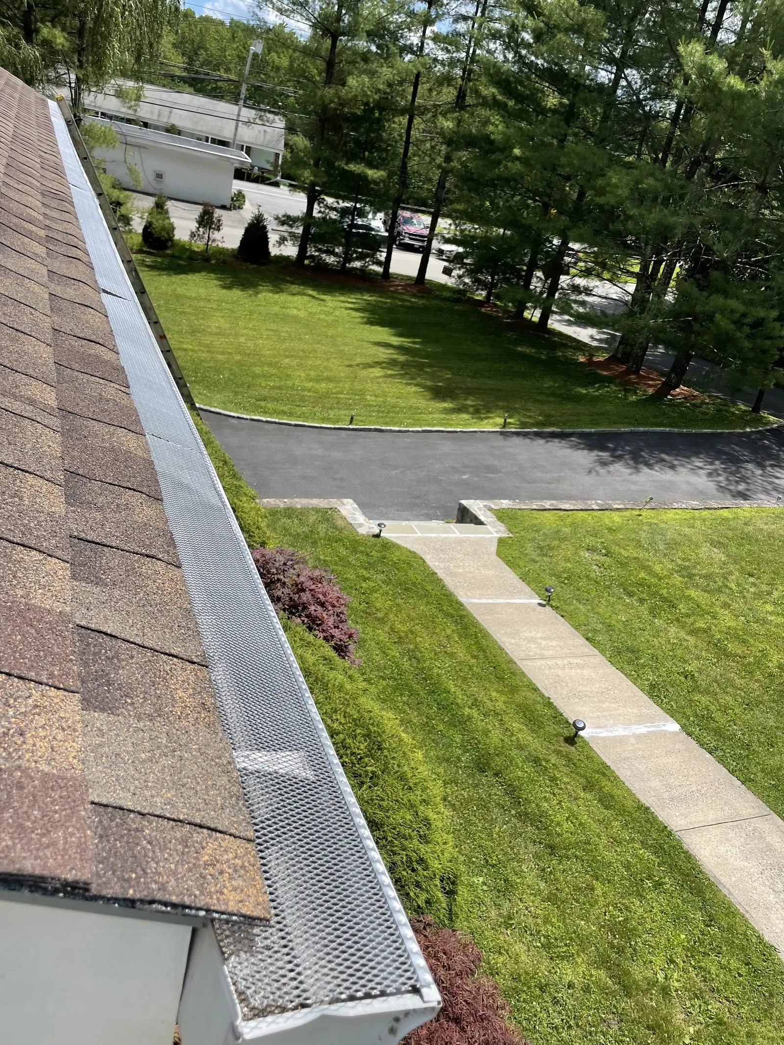 Freshly installed gutter guard running along a roofline above a manicured lawn
