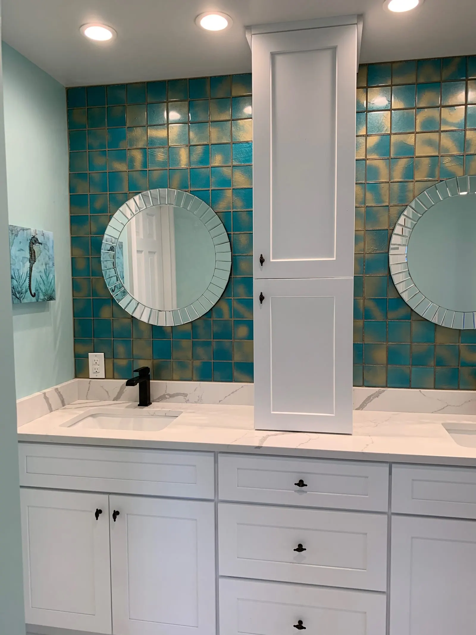 Finished bathroom remodel with a white double vanity, round mirrors and teal glass tile