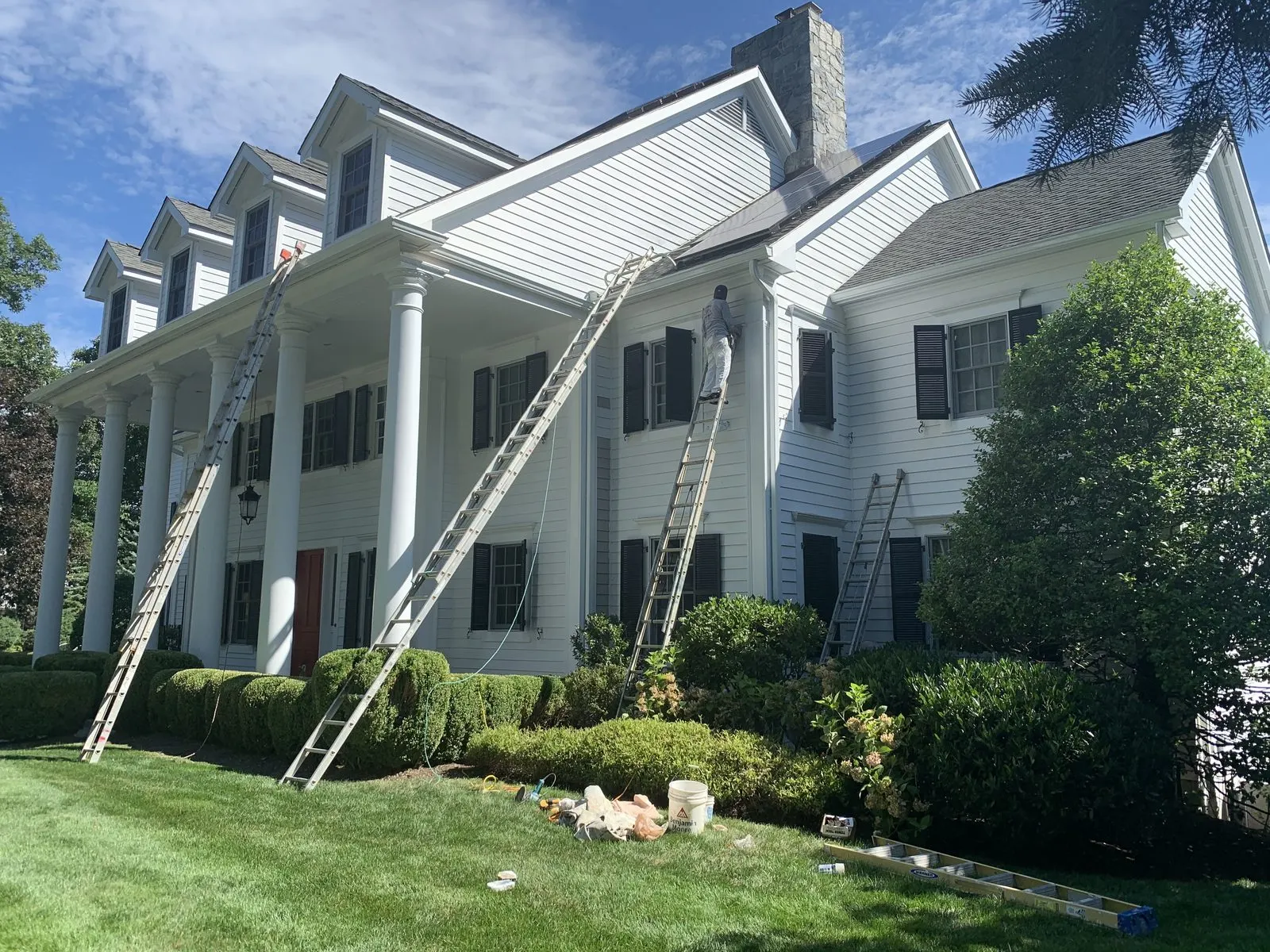 White colonial house with ladders