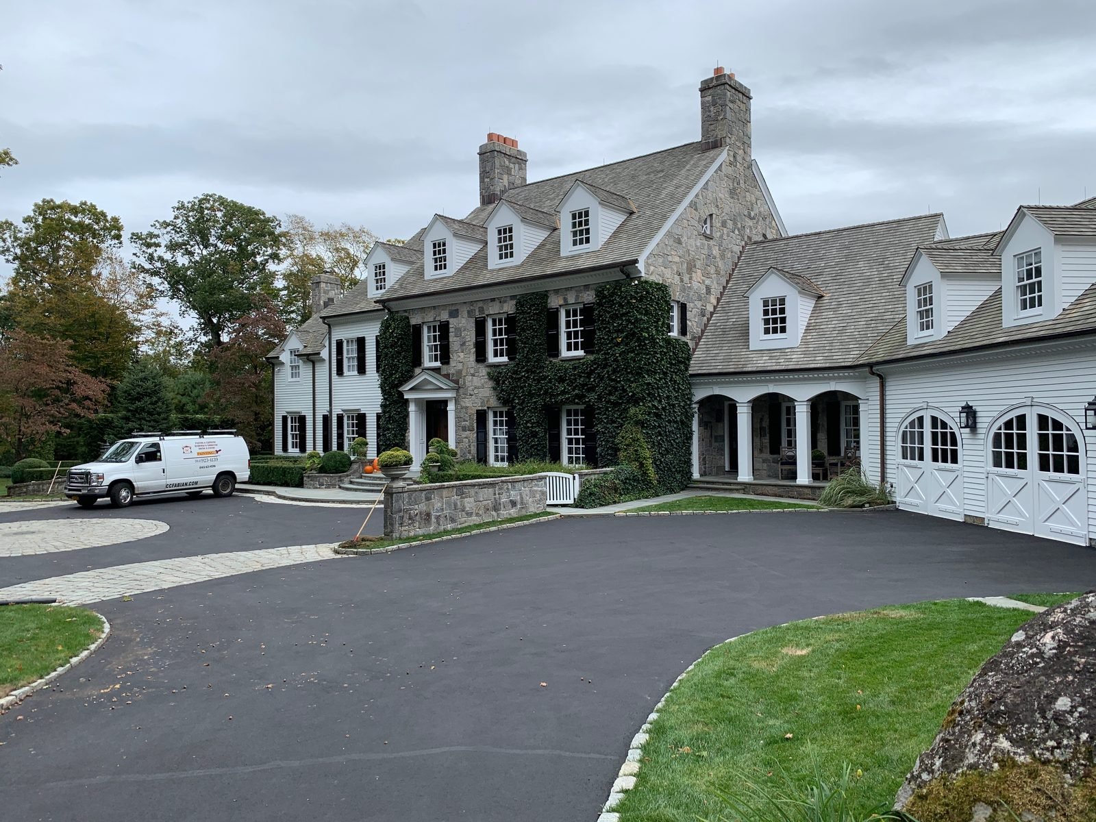 A well-maintained stone colonial home with the CC Fabian van in the driveway.