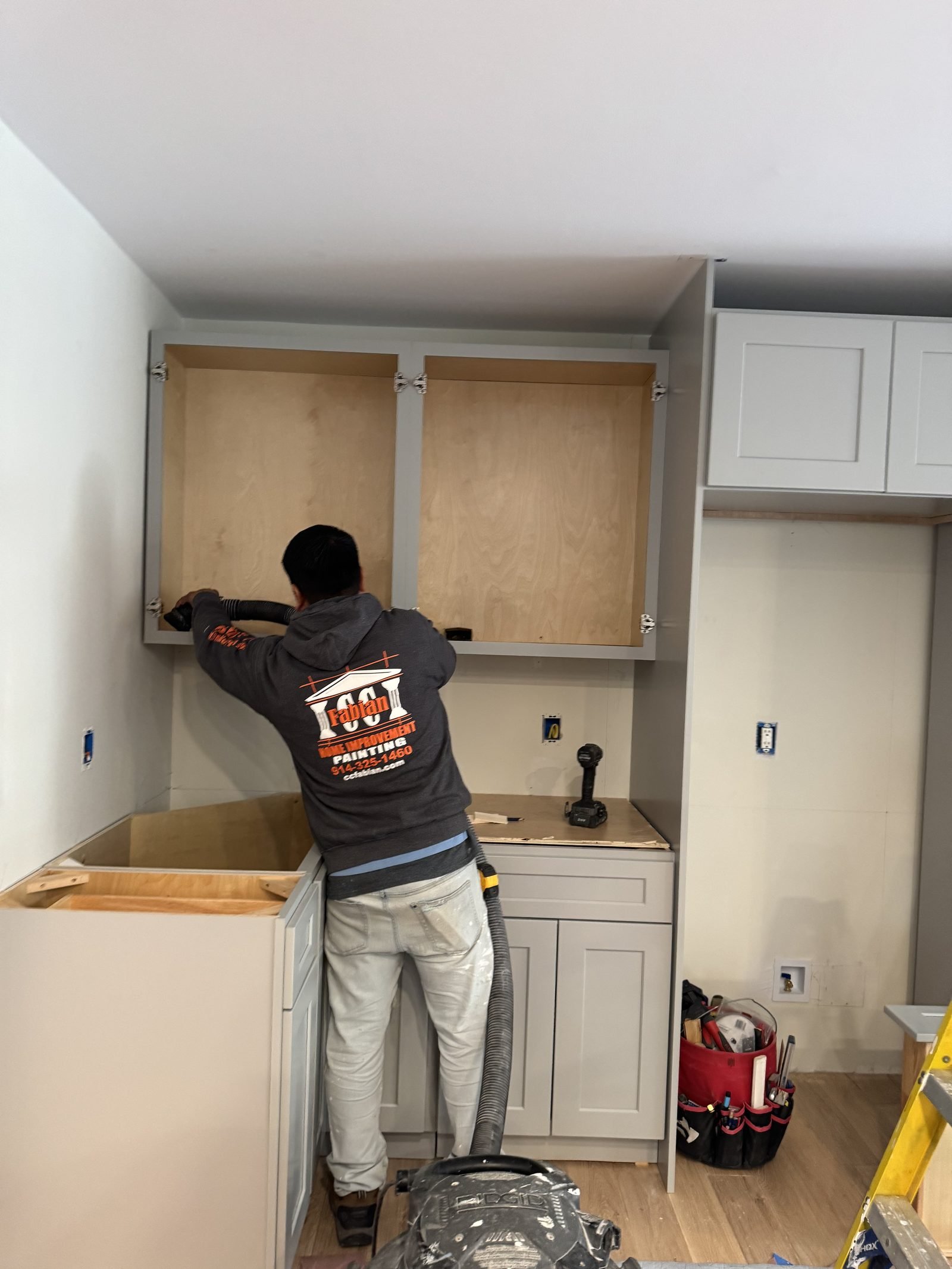 CC Fabian carpenter installing custom kitchen cabinetry.