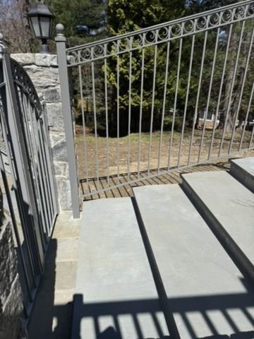 Black aluminum fence and gate along a bluestone walkway