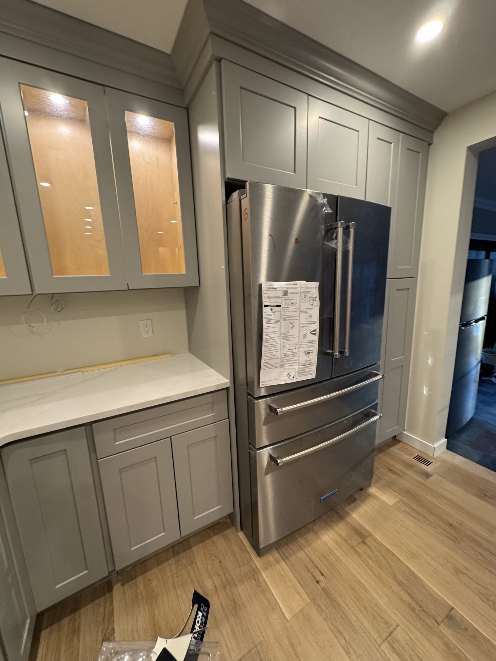 Gray shaker kitchen with glass display cabinets and stainless refrigerator
