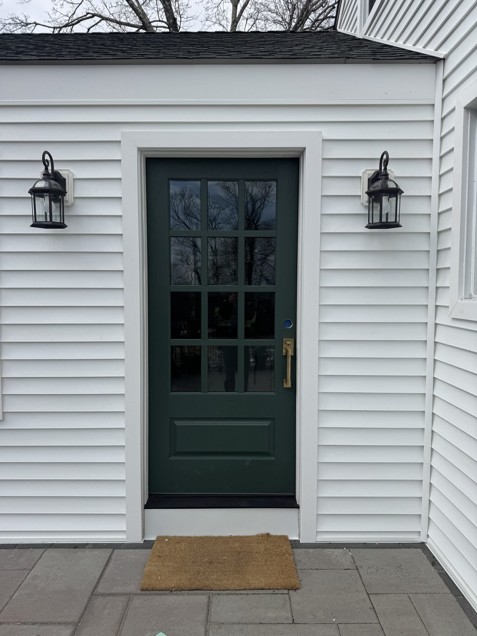 Entry detail with white siding, a green door and carriage lights